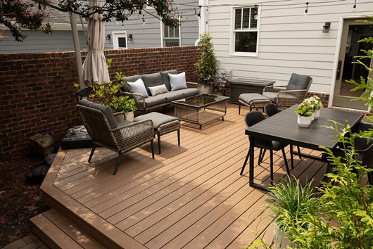 Modern outdoor composite decking area with dining furniture and lounge seating in a private garden space.