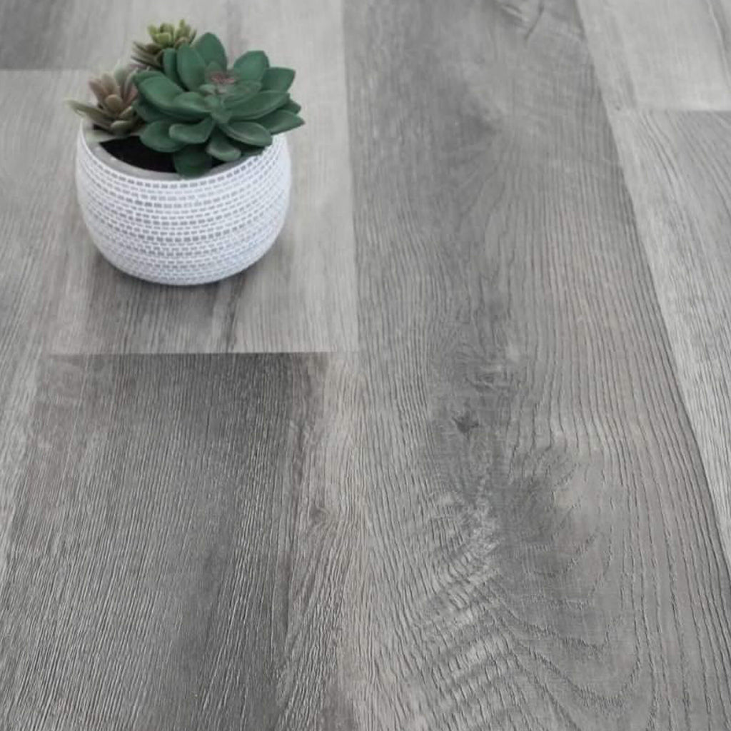 Close-up of Conwy Grey Rigid LVT Flooring with a potted plant.