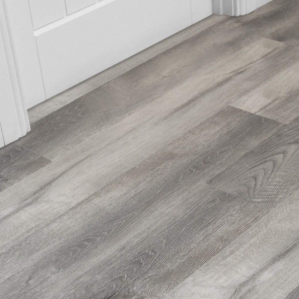 Close-up of Conwy Grey Rigid LVT Flooring with white skirting board and door.