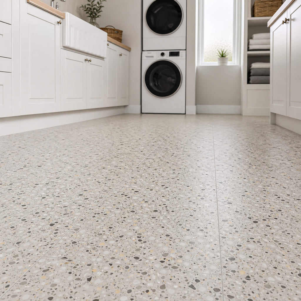 Modern laundry room with white cabinets, washing machines, and a Close-up of Milano Terrazzo Rigid LVT flooring.