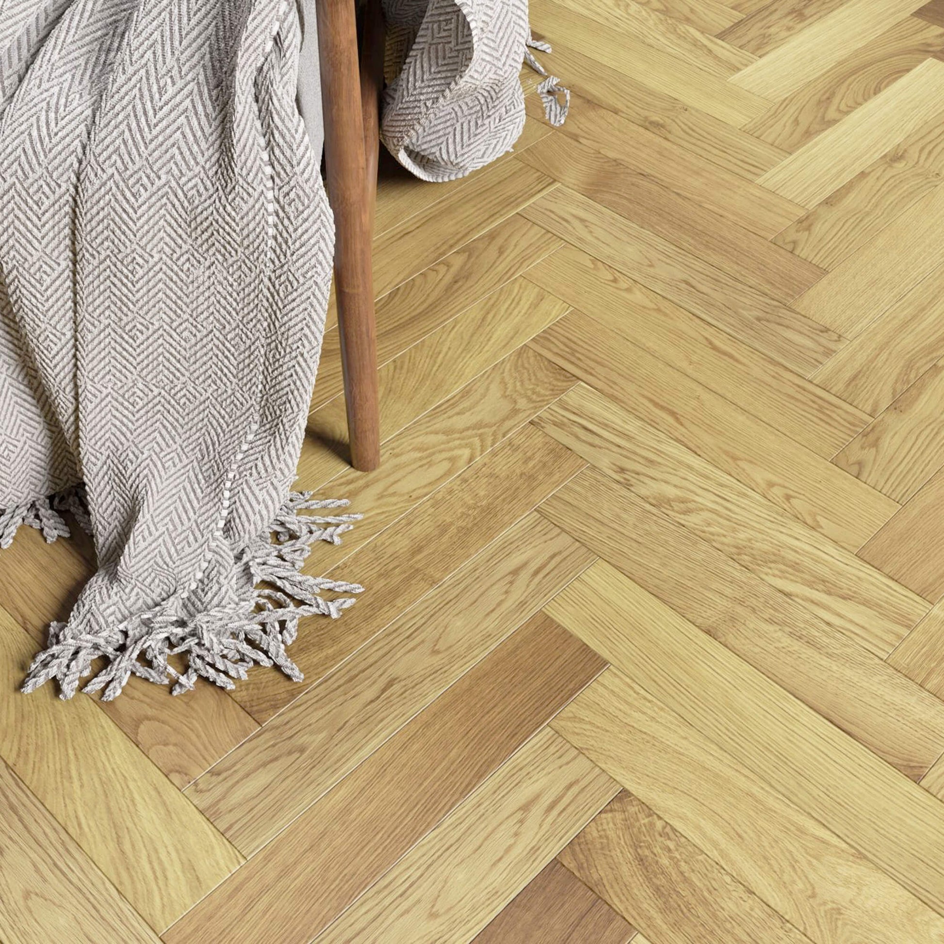 Natural Oak Herringbone Lacquered Engineered Wood Flooring and a textured blanket draped over a chair.