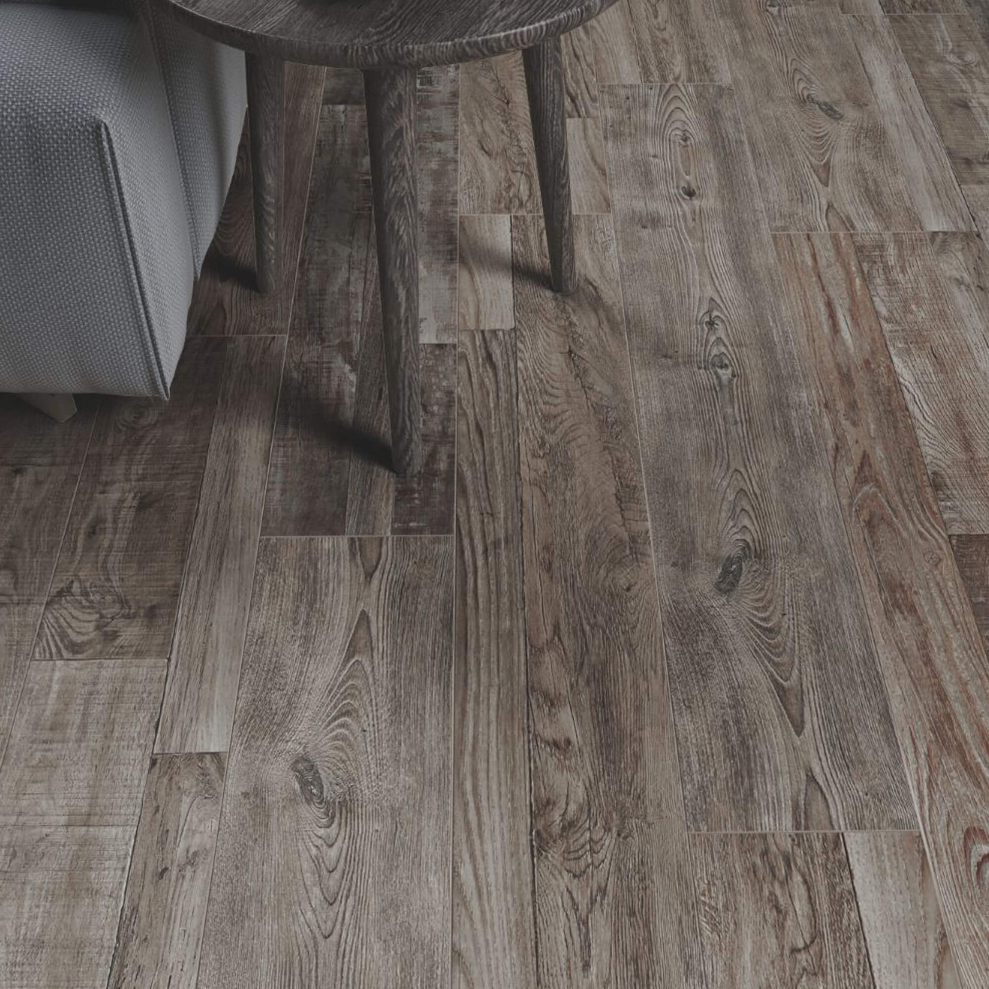 Reclaimed Oak Country Laminate Flooring with an edge of a sofa and table in the corner.