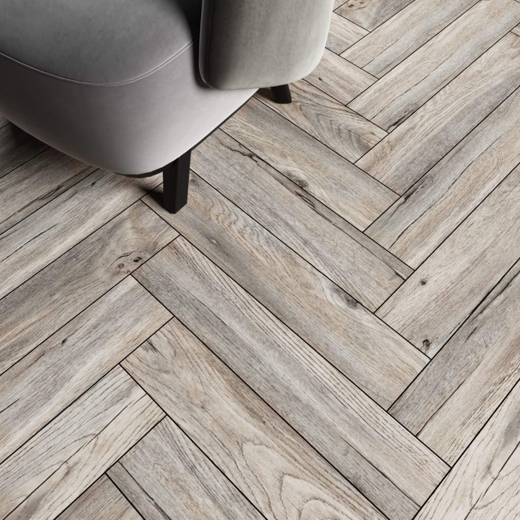 Riviera Oak Rigid LVT Herringbone Flooring and a grey chair in the corner.
