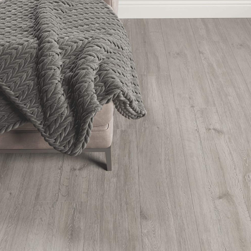Rockford Oak Laminate Flooring in a living room setting with a sofa and rug in the corner.