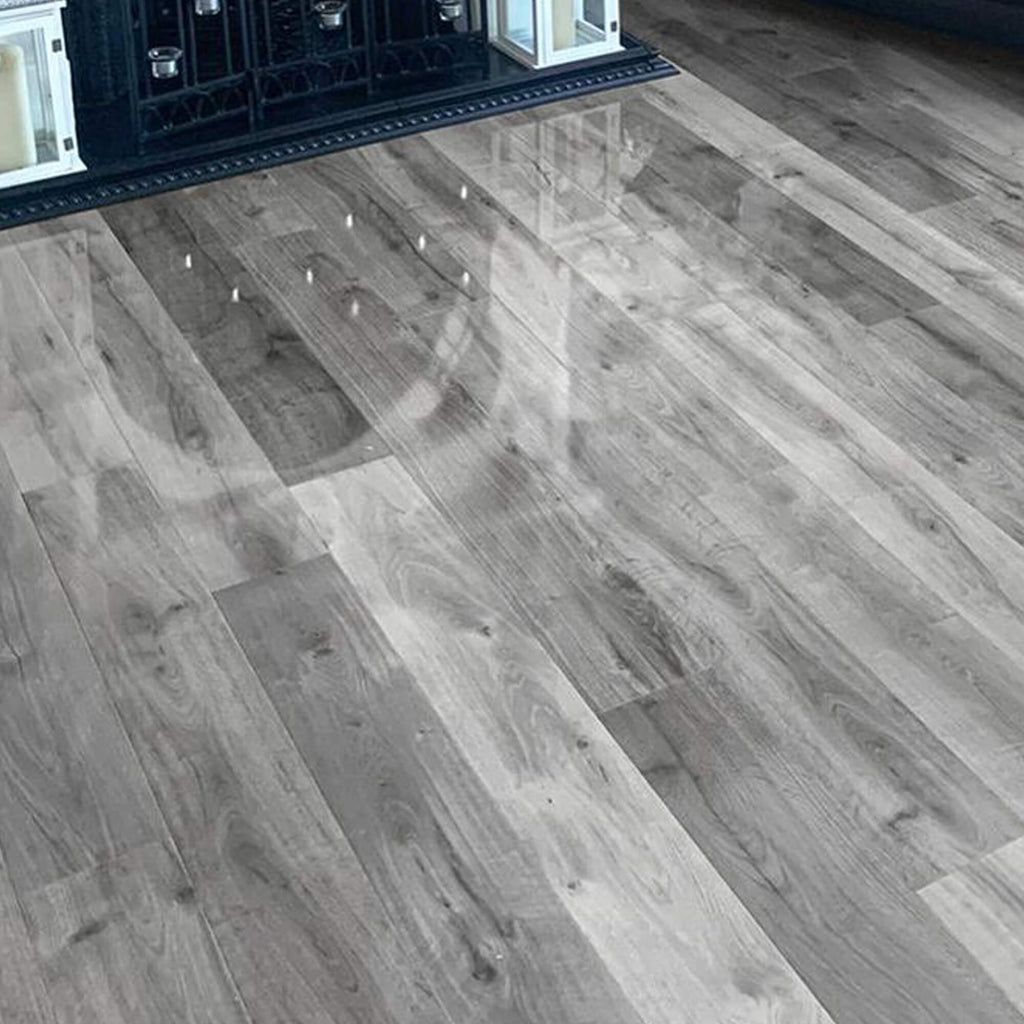 Uptown Oak Gloss Laminate Flooring in a living room setting with a fireplace I the background.