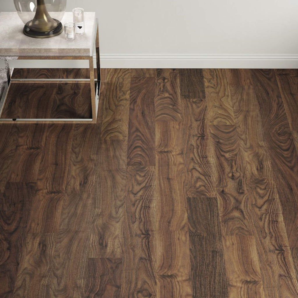 Walnut Prestige Laminate Flooring in a living room background with a table and lamp in the corner.