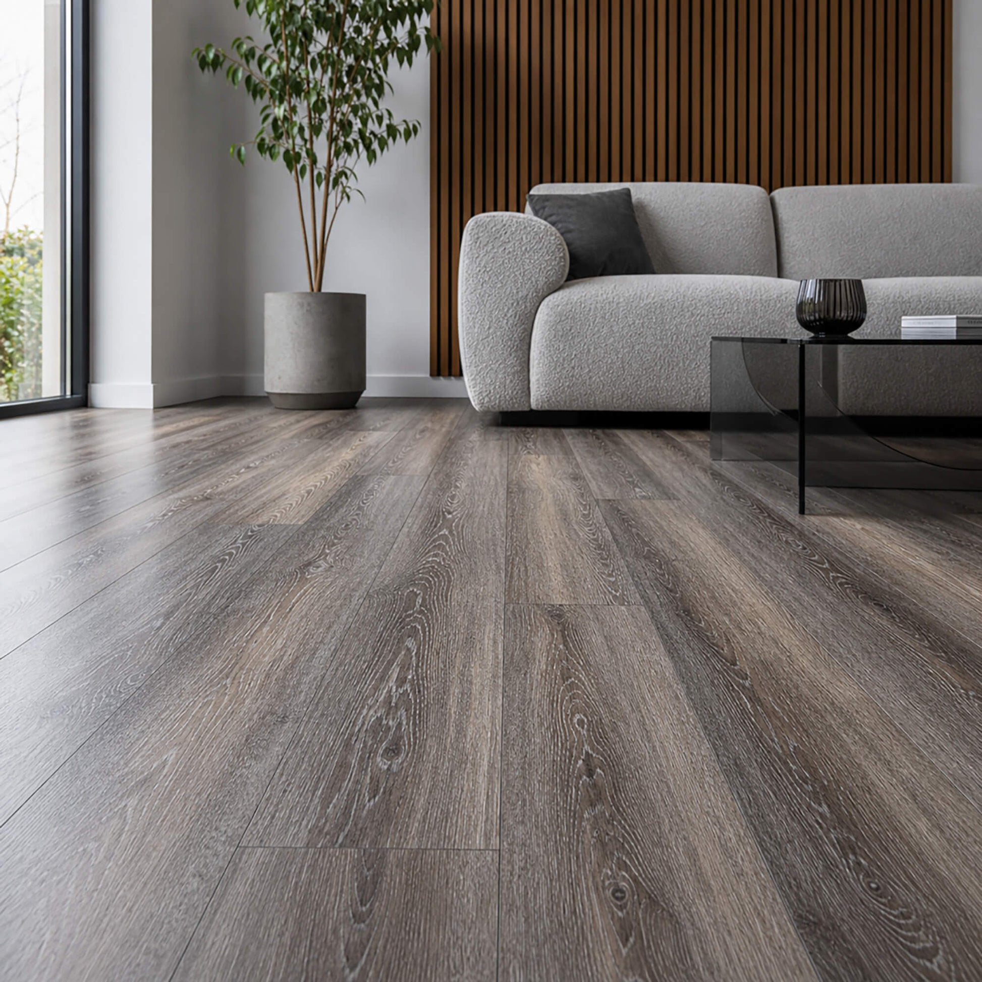 Weathered Oak Rigid LVT flooring in a living room setting with a sofa, plant and coffee table.