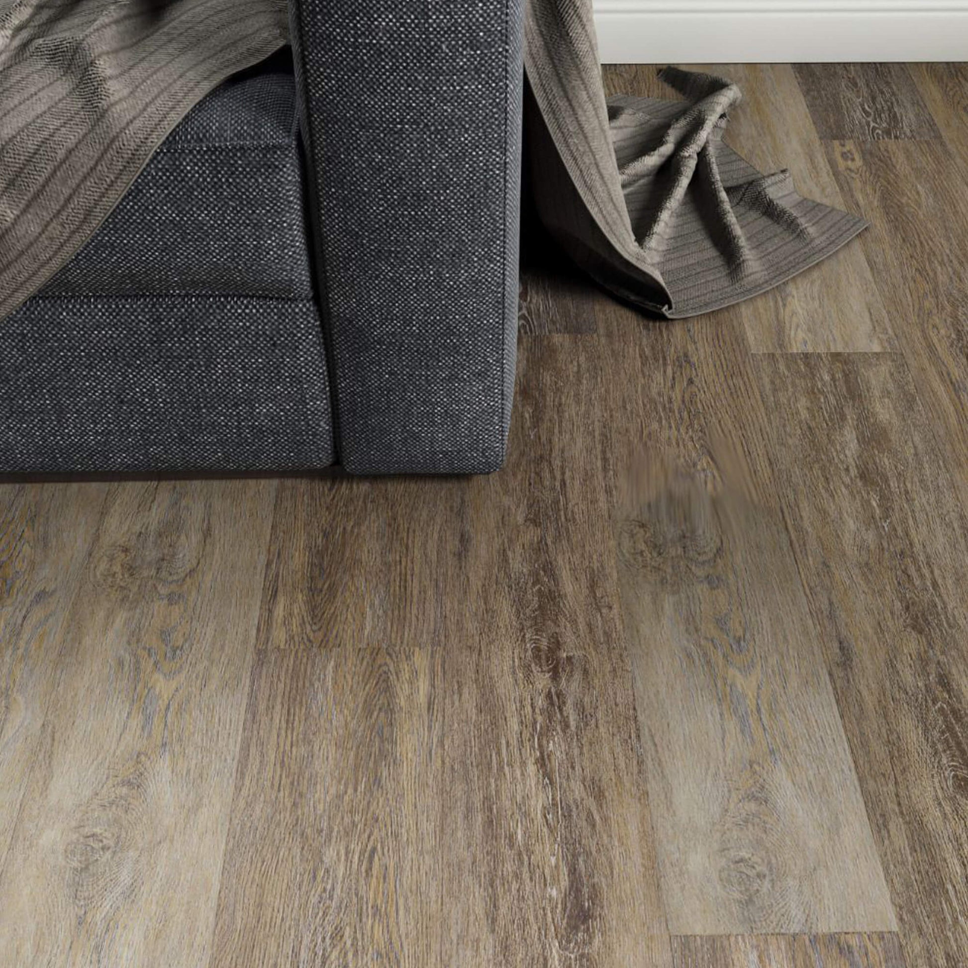 Weathered Oak Prestige Laminate Flooring in a living room setting with a sofa and rug in the background.