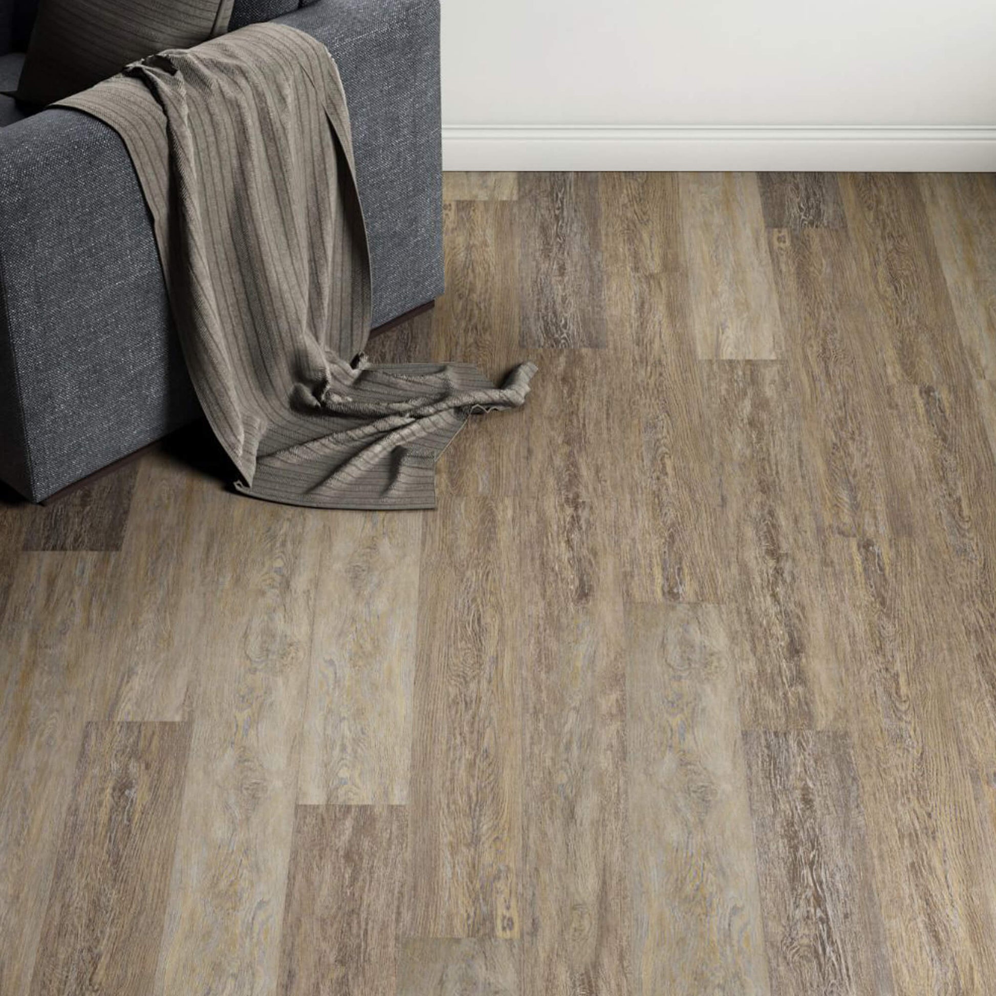 Weathered Oak Prestige Laminate Flooring in a living room setting with a sofa and rug and back wall in the background.